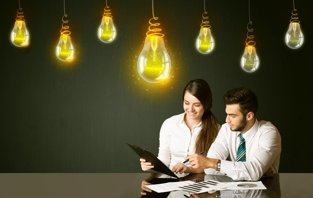 People sitting at the black table with idea bulbs on the background